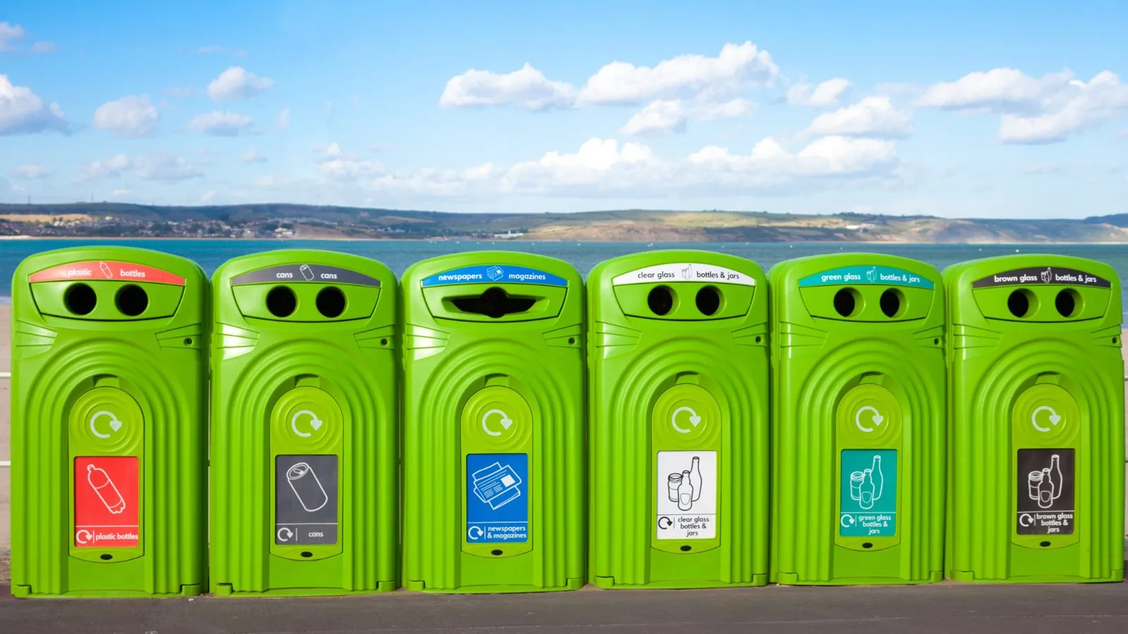 A row of green recycling banks by the sea
